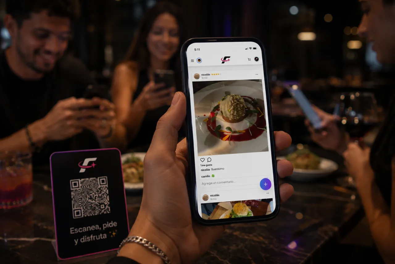 Feed de FIDELYA Space en el celular junto al QR de mesa